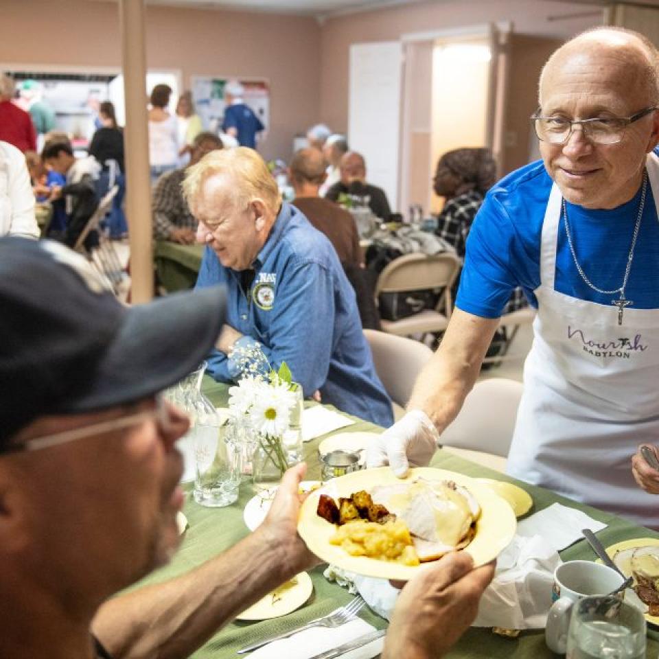 A Nourish Babylon volunteer serves a healthy, homemade meal to a community member at Christ Episcopal Church in Babylon during their weekly Monday night community meal.