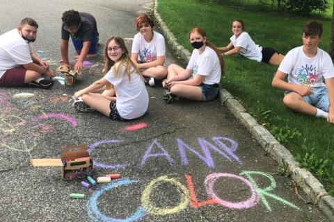 Camp Color participants draw with chalk on the sidewalk